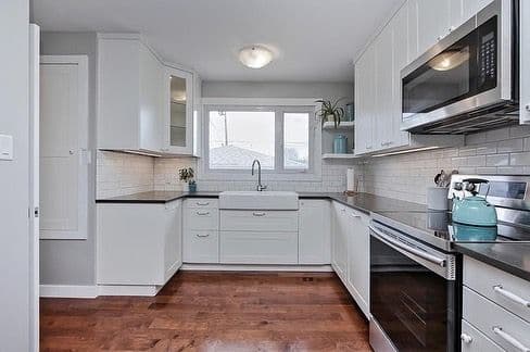 A white kitchen with a farmhouse sink and subway tile